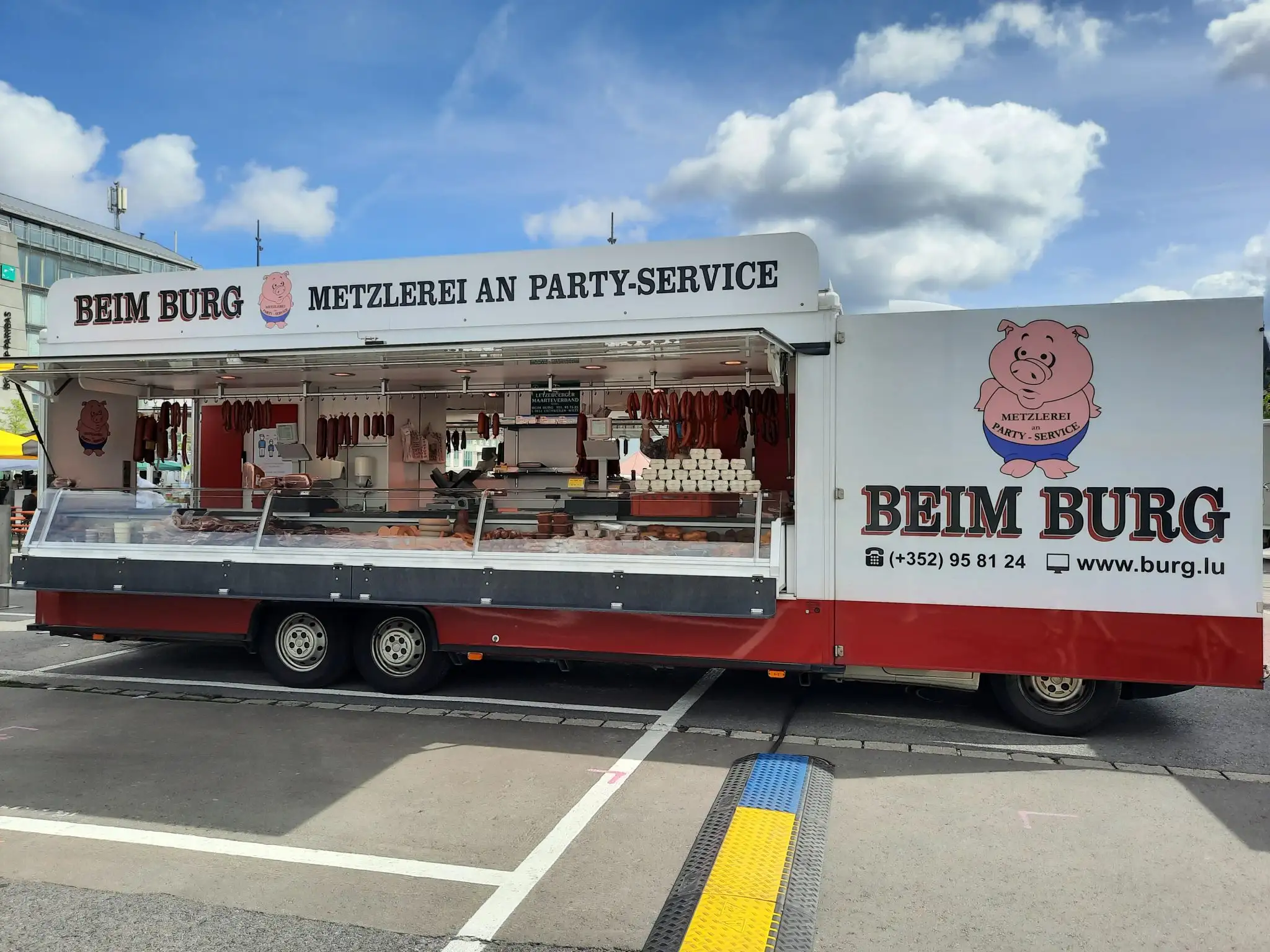 Der Verkaufswagen Beim Burg — Metzlerei an Party-Service — auf einem Wochenmarkt, die Theke reich gefüllt mit hausgemachter Wurst